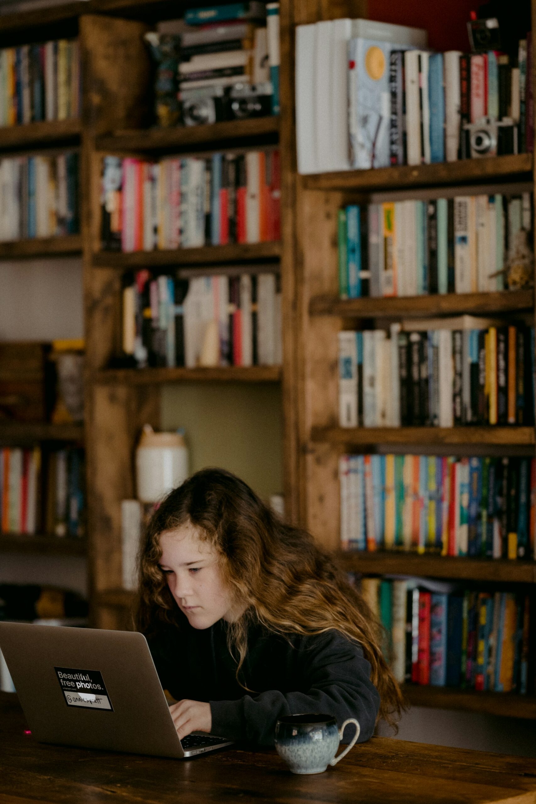 Girl in library doing homework on laptop